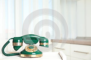 Vintage corded phone on white table indoors. Space for text