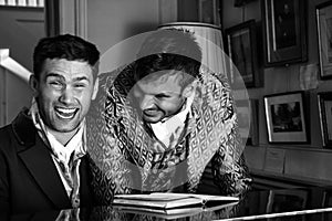 Vintage couple in period costume sitting around piano playing tunes and singing songs