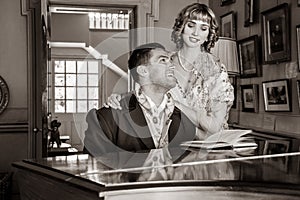 Vintage couple in period costume sitting around piano playing tunes and singing songs
