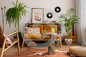 Vintage and cozy space of dining room with mock up poster frame, yellow sofa, marble coffee table, guitar, armchair plants,