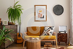 Vintage and cozy space of dining room with mock up poster frame, yellow sofa, wooden coffee table, guitar, plants, commode,