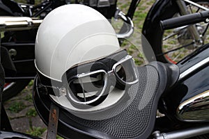 Vintage crash helmet and protective goggles on motorcycle seat