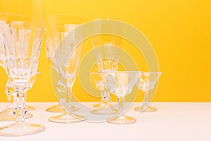 Vintage crystal glasses in front of yellow background.