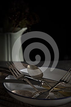 Vintage cutlery arranged in a tin plate with a jug in the background