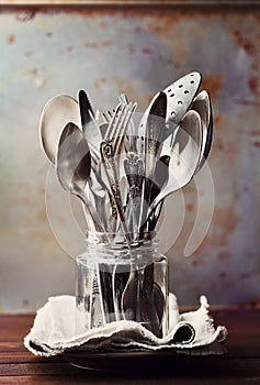 Vintage cutlery in jar on rustic background, old kitchen tools