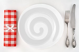 Vintage cutlery set with fork, knife, plate and red checkered napkin.