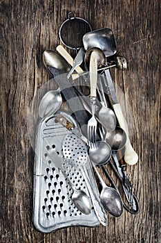 Vintage cutlery - spoons, forks, knives and grater, on wooden background