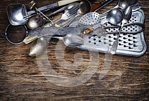 Vintage cutlery - spoons, forks, knives and grater, on wooden background