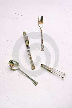 Vintage cutlery on a white background. Silver spoon, fork, knife and tongs in horizontal position. Flat lay, top view