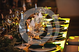 Vintage decoration of reception dinner table. Rustic wedding table setting in fancy European restaurant. Wine glasses, plates,