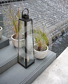 Vintage decorative glass lamp on concrete steps against waterfall background.