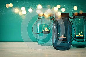 vintage decorative magical mason jars with candle light on wooden table