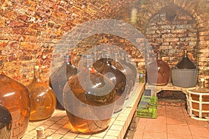 Vintage demijohns in a traditional wine cellar. Demijohn wine bottles