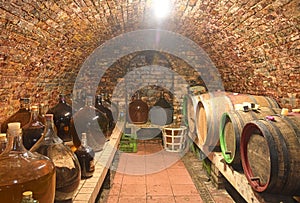 Vintage demijohns in a traditional wine cellar. Demijohn wine bottles and wooden wine barrels
