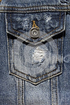 Vintage denim texture background: jacket close-up. Blue torn denim pocket. Stylish torn denim background.