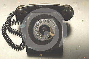 Vintage dial telephone with a coiled cable and a handset.