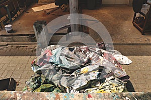 Vintage Dirty Crumpled Tarpaulin Sheet with Colorful Paint in Cluttered Garage/ Junkyard/ Storeroom