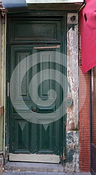 Vintage door with framed wooden panels painted in dark green color. Shabby stone walls around entrance of retro building in Paris