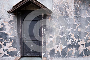 Vintage door with a wooden canopy on the background of the shabby wall, copy space