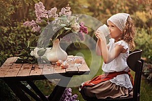 Vintage dressed child girl on garden tea party in spring