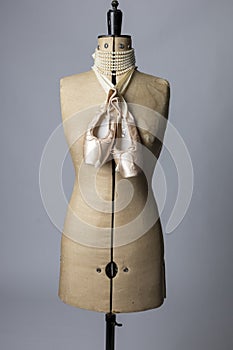 Vintage dressmakers dummy with ballet shoes around its neck photo