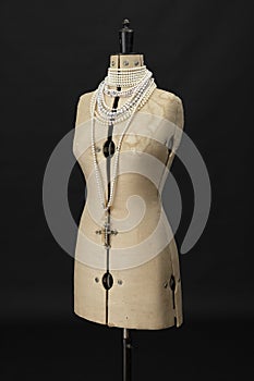 Vintage dressmakers dummy with pearl necklaces around its neck photo