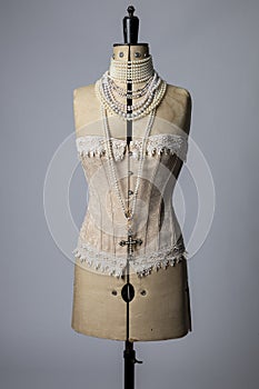 Vintage dressmakers dummy wearing a corset and with pearl necklaces around its neck photo