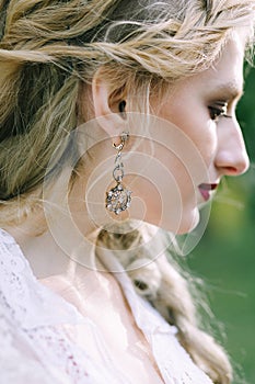 Vintage earring on the bride`s ear. Close-up portrait of the bride. Artwork.