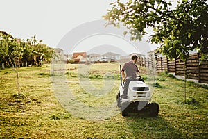 Vintage effect of landscaping works. Male worker riding a tractor grass trimmer
