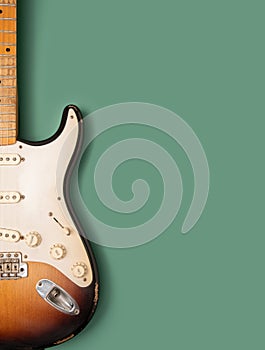 Vintage electric guitar against pastel green background.