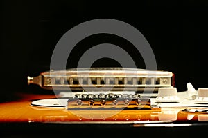 Vintage electric guitar with harmonica on black background