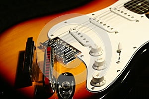 Vintage electric guitar with harmonica on black background