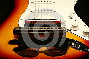 Vintage electric guitar, harmonica, sunglasses on black background