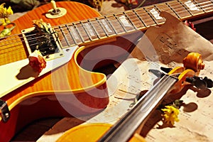 Vintage electric guitar, rare violin, dried flowers and old notes on wooden background