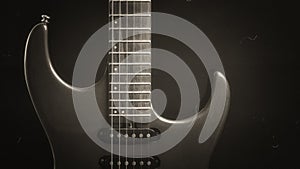 A vintage electric guitar standing upright with textured noir concept as black silver wallpaper.