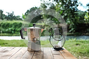 Vintage electric lantern and glass dripper carafe on a folding table for camping at river side blur background