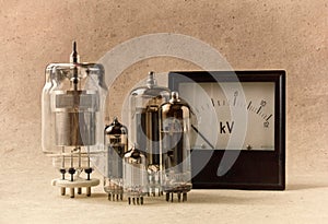 Vintage electronic background with vacuum tubes and voltmeter on kraft paper.