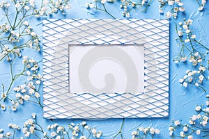 Vintage empty frame and fresh white gypsofila flowers on blue textured background photo