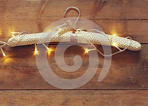 Vintage fabric hanger with gold Christmas warm gold garland lights on wooden rustic background. filtered image
