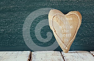 Vintage fabric heart on wooden table in front of blackboard.