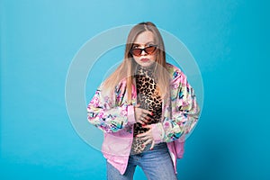 Vintage fashion look concept - pretty young woman wearing a retro pink jacket and leopard body on blue background