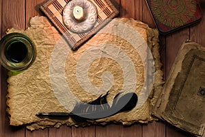 Vintage feather with paper and ink on table in light of candle