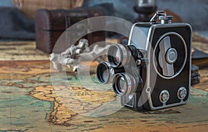 Vintage film camera stands on an old nautical chart against the background of a forged chest.