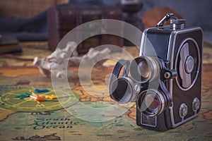 vintage film camera stands on an old nautical chart against the background of a forged chest.