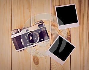 Vintage film camera and two blank photo frames on wooden table.