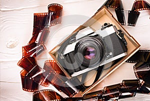 Vintage film camera in a wooden box on wooden white background with film