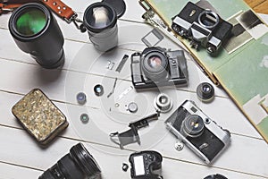 Vintage film cameras, their components, modern digital cameras and lenses on wooden white background technology development conce