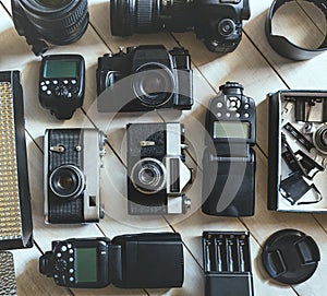 Vintage Film And DSLR Camera, Photo Accessories On White Wooden Background Technology Development Concept. Top View