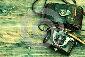 Vintage film photo camera with leather bag on wooden background