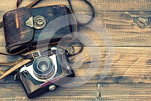 Vintage film photo camera with leather bag on wooden background